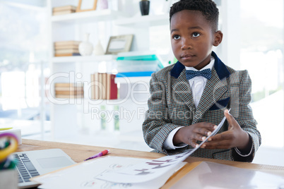 Businessman holding documents while sitting at desk