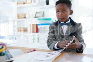 Businessman holding documents while sitting at desk