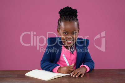 Portrait of smiling businesswoman writing report