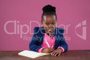 Portrait of smiling businesswoman writing report