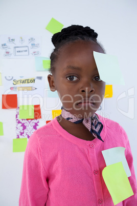 Businesswoman with adhesive notes looking away against whiteboard