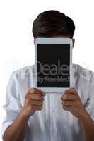 Teenage boy hiding his face behind digital tablet