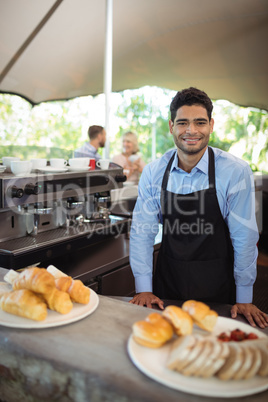 Smiling waiter standing near counter at restaurant