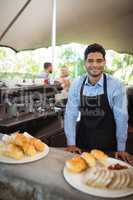 Smiling waiter standing near counter at restaurant