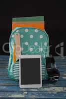 Schoolbag with various supplies and digital tablet on table