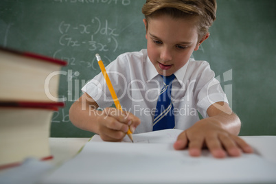 Schoolboy doing his homework in classroom