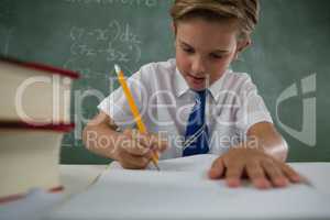 Schoolboy doing his homework in classroom