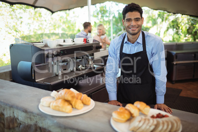 Smiling waiter standing near counter at restaurant