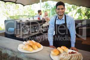 Smiling waiter standing near counter at restaurant