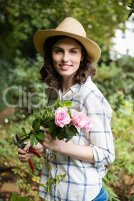 Woman trimming flowers with pruning shears in garden on a sunny day