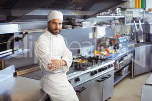 Portrait of smiling chef standing with arms crossed in commercial kitchen