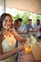 Smiling woman using mobile phone while having a glass of beer in restaurant