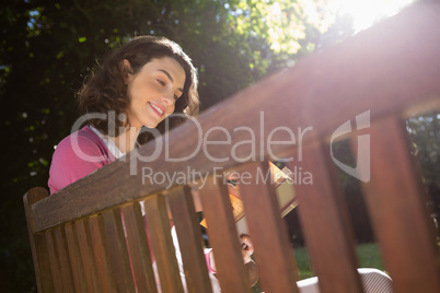 Woman sitting on bench and reading book