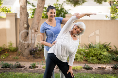 Portrait of smiling trainer assisting senior woman