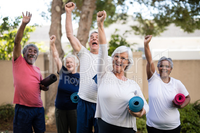 Cheerful multi-ethnic seniors with exercise mats at park