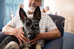 Midsection of senior man holding puppy while sitting on armchair
