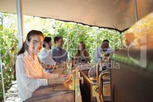 Smiling woman using mobile phone while having a glass of champagne in restaurant