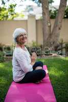 Side view of smiling senior woman meditating in prayer position