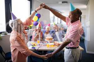 Senior couple making frame against friends at birthday party