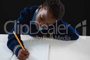 Schoolgirl doing his homework against black background