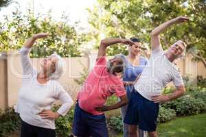 Female trainer guiding senior people while exercising