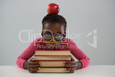 Schoolgirl leaning on books stack against white background