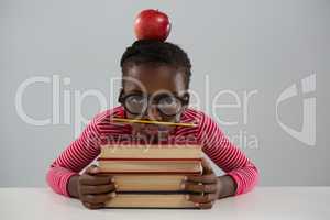 Schoolgirl leaning on books stack against white background