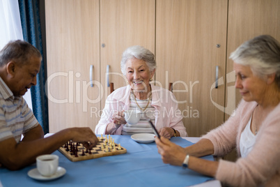 Smiling woman having coffee while sitting with friends