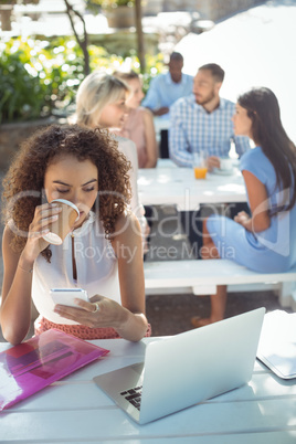 Beautiful woman using mobile phone while having coffee