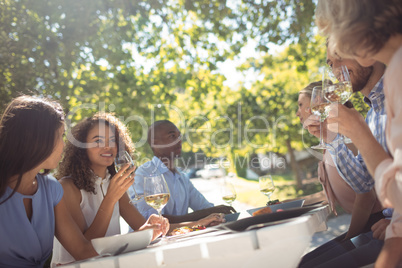 Happy friends interacting while having glass of wine