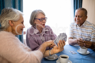 Smiling senior woman showing cards to friends while playing