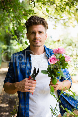 Man trimming flowers with pruning shears in garden on a sunny day