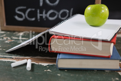 Books, apple and slate board with back to school text