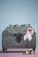 Close-up of pink Breast Cancer Awareness ribbon with rings and chest on table