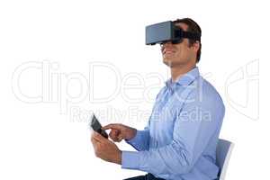 Smiling mature businessman wearing vr glasses while using digital tablet