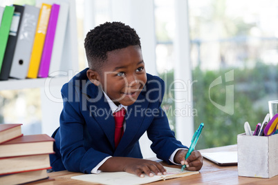 Smiling businessman looking away while writing on book