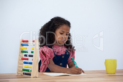Businesswoman writing on book while sitting at desk