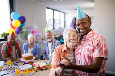 Portrait of senior couple wearing party hats standing by table
