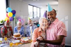 Portrait of senior couple wearing party hats standing by table