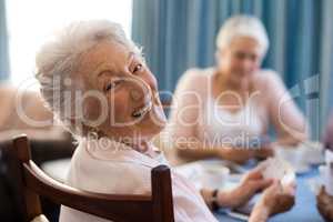 Smiling senior woman playing cards with friends