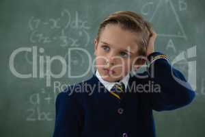 Schoolboy standing against chalkboard
