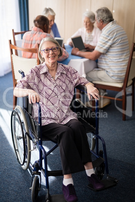 Portrait of smiling disabled senior woman sitting on wheelchair against friends