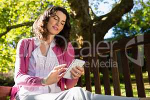 Woman sitting on bench and using mobile phone