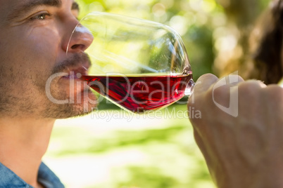 Man drinking glass of red wine in park