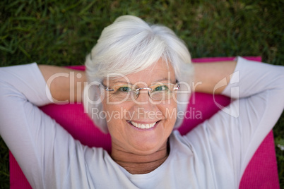 Portrait of smiling senior woman lying on exercise mat