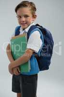 Portrait of happy schoolboy holding books against white background