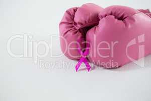 Close-up of pink Breast Cancer Awareness ribbon with boxing gloves pair