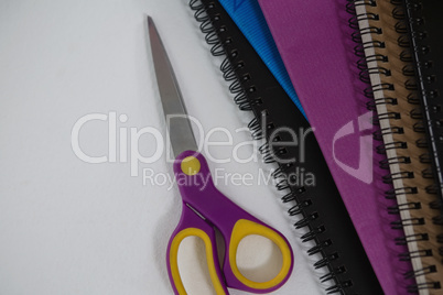 Scissors and spiral books on white background