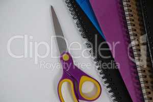 Scissors and spiral books on white background