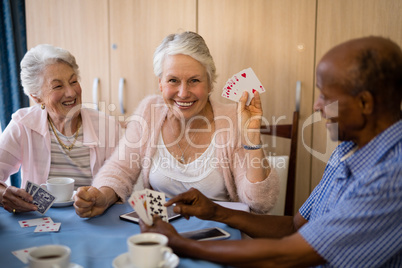 Happy senior people playing cards while having coffee